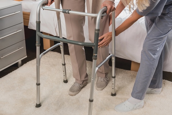 elderly person in walker being assisted in nursing home