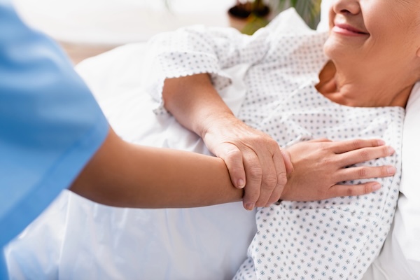senior woman in hospital bed with caring nurse