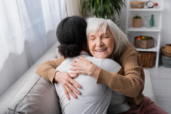 elderly woman hugging a person helping her